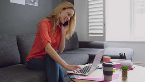 Female-executive-talking-on-mobile-phone-while-using-laptop-in-a-modern-office-4k