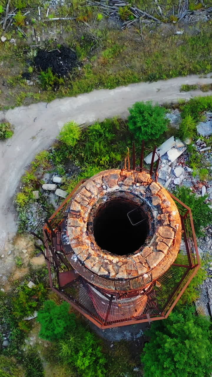 Old industrial chimney. Brick pipe of long built on the desolate factory position. Top aerial view. Vertical video
