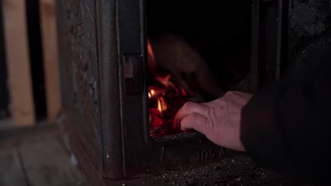 hand piling up woods inside furnace with fire