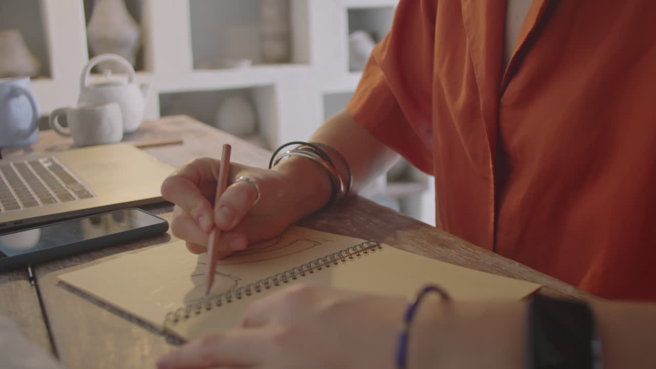Female Artist Drawing Sketch at Desk in Pottery Workshop