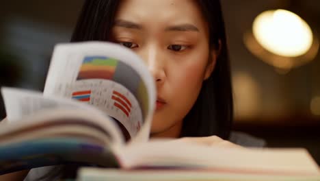 intense focus: a student deeply engaged in reading and learning, turning pages with care in a quiet study environment