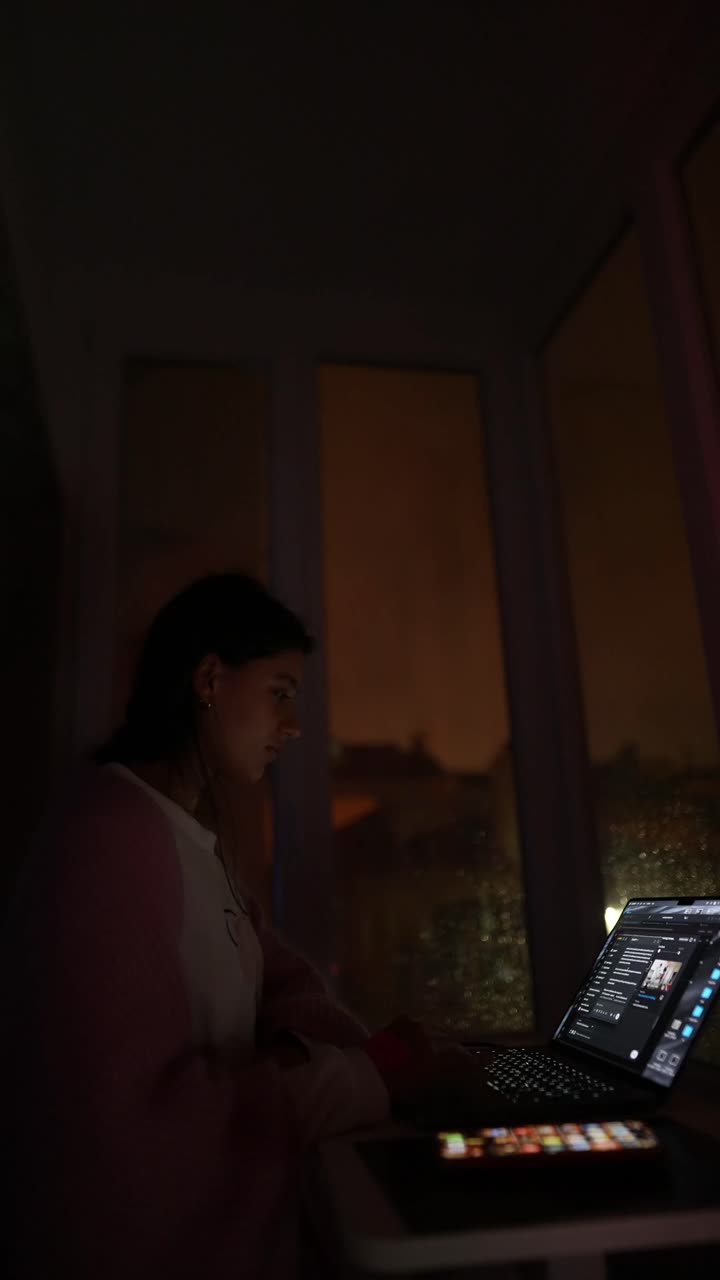 Donna che lavora al portatile di notte vicino alla finestra