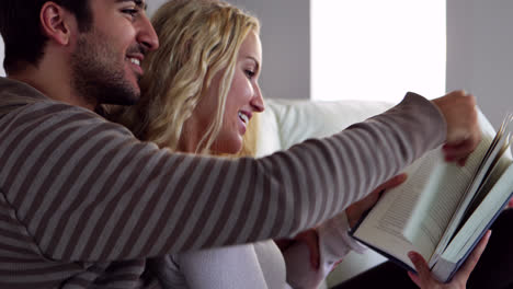 happy young couple reading together on the couch