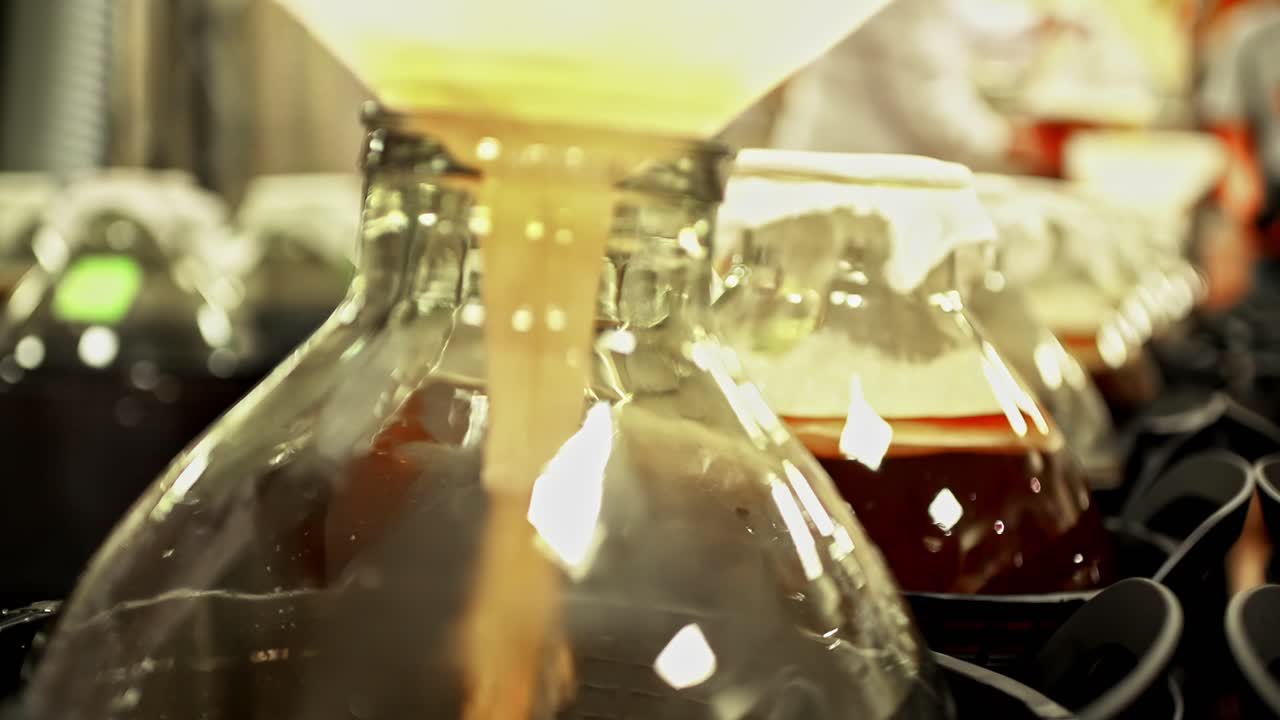 Kombucha fermented tea drink. how is made pouring liquid into glass bottle factory