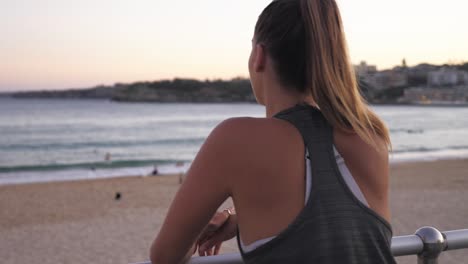 a beautiful woman stopping her jog to enjoy the stunning scenery of bondi beach, australia - slow motion