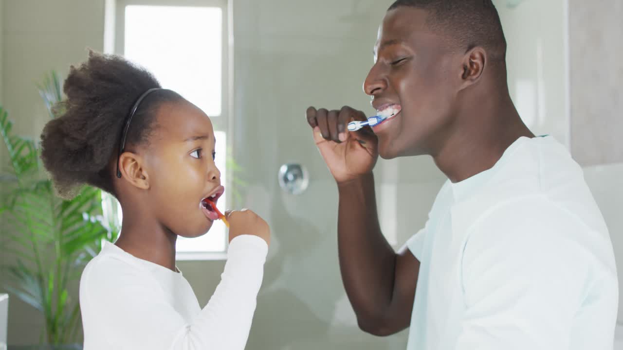 Video of african american father and daughter brushing teeth