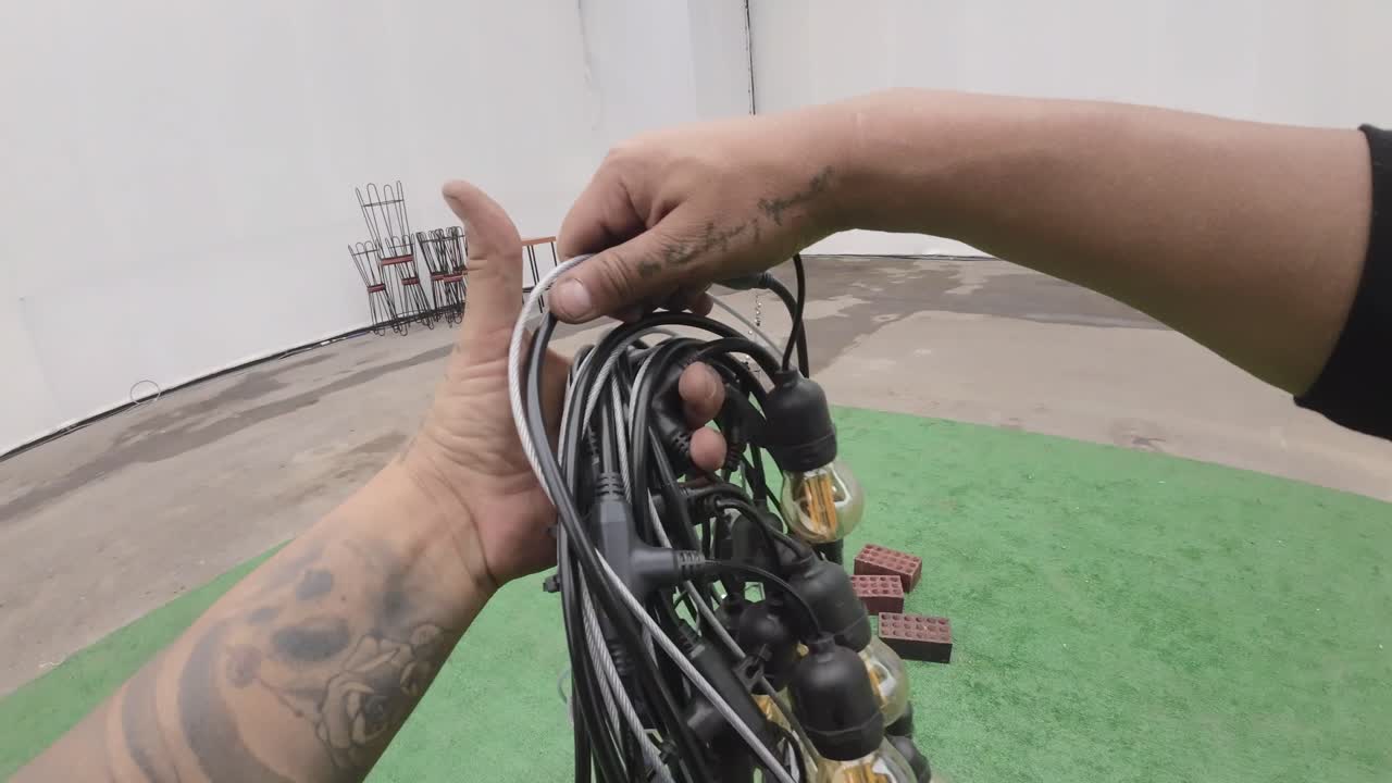 Person Uncoiling String Lights with Edison Bulbs for Event Setup