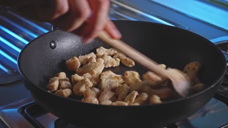 cooking and stirring pan-grilled chicken breast in bite-size cuts