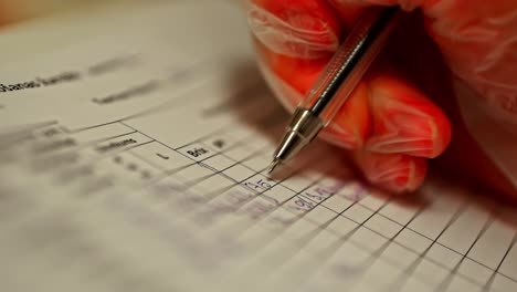 Gloved hand writing data into quality control sheet during inspection