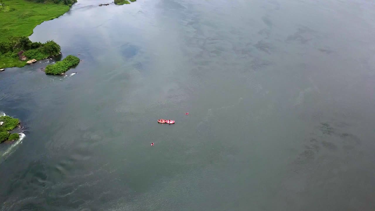 High aerial orbit over white water rafting on the Nile River near Jinja, Uganda as Red rafts navigate swirling currents and green islands in Africa’s iconic adventure corridor