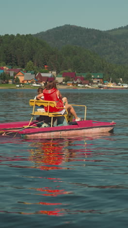 mother and child pedal together on catamaran riding along peaceful river against village enjoying scenic view. having fun and observing beauty of nature. family vacation