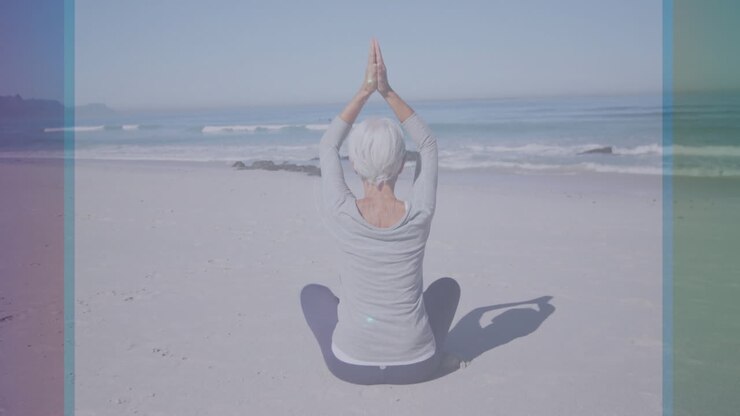 Persona anziana che pratica yoga sulla spiaggia con un'animazione circolare digitale sovrapposta.