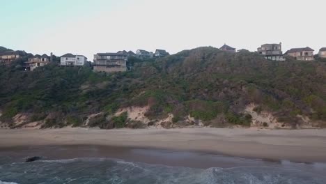 Homes-on-rugged-steep-shoreline-at-Brenton-on-Sea,-dolly-aerial-right