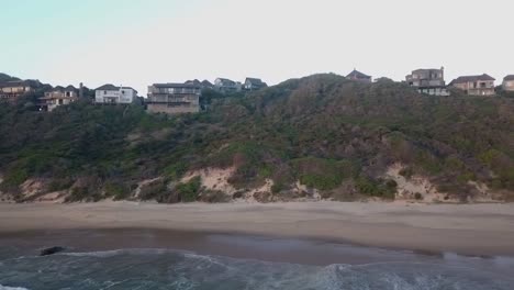 homes on rugged steep shoreline at brenton on sea, dolly aerial right