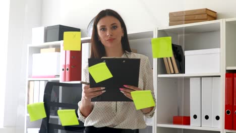 businesswoman making notes in documents standing near glass wall