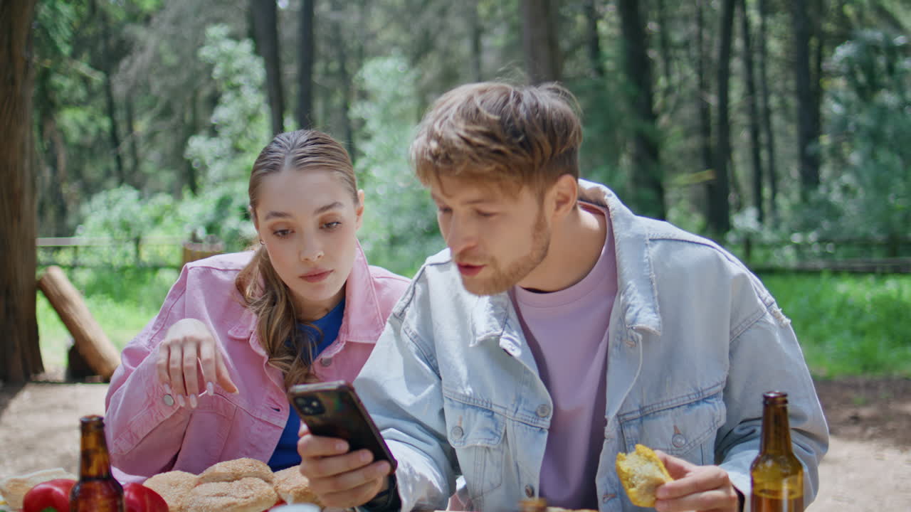 Picnic friends looking smartphone screen enjoying summer forest nature closeup