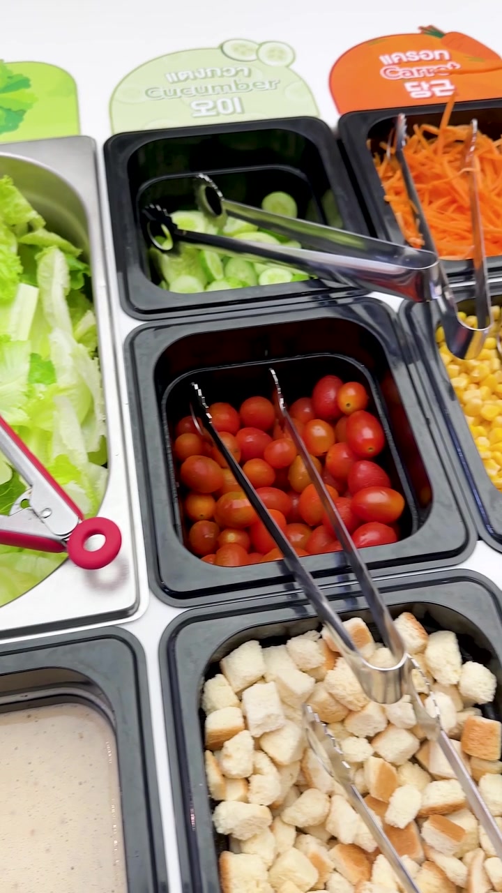 A high-angle panning shot across a vibrant salad bar buffet in Bangkok, Thailand.