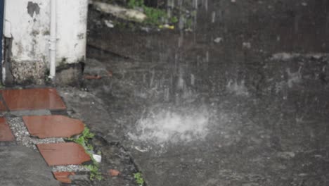 rain pouring down on a pavement next to a house