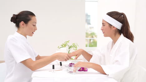 beautician filing female clients nails at spa beauty salon