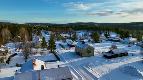 Skorped,-Suecia-En-Invierno-Con-Casas-Y-árboles-Cubiertos-De-Nieve,-Cielo-Azul,-Vista-Aérea