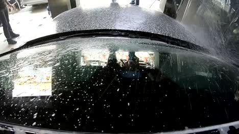 a car wash employee uses a hand wash to foam the car