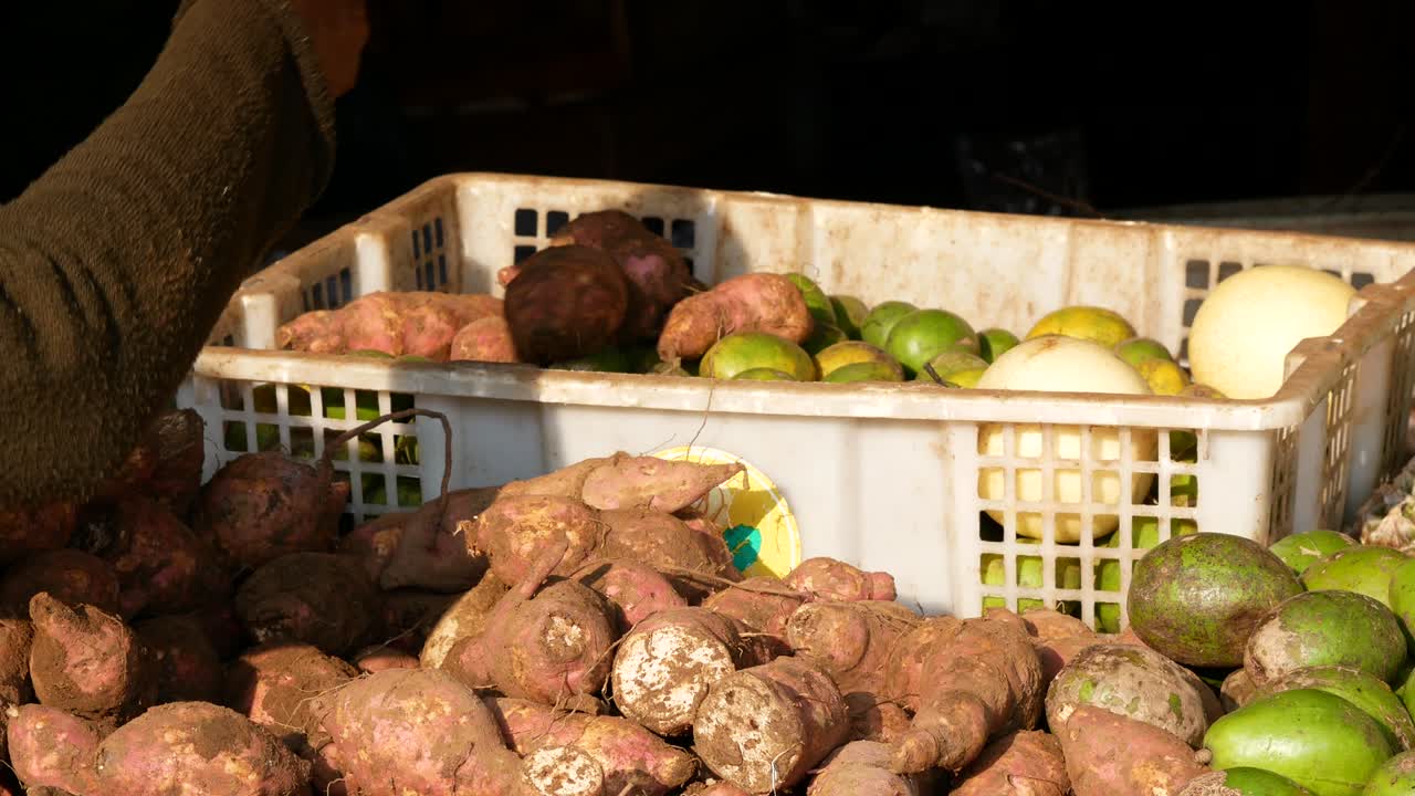 una mujer indonesia está eligiendo ñames en un mercado húmedo tradicional.