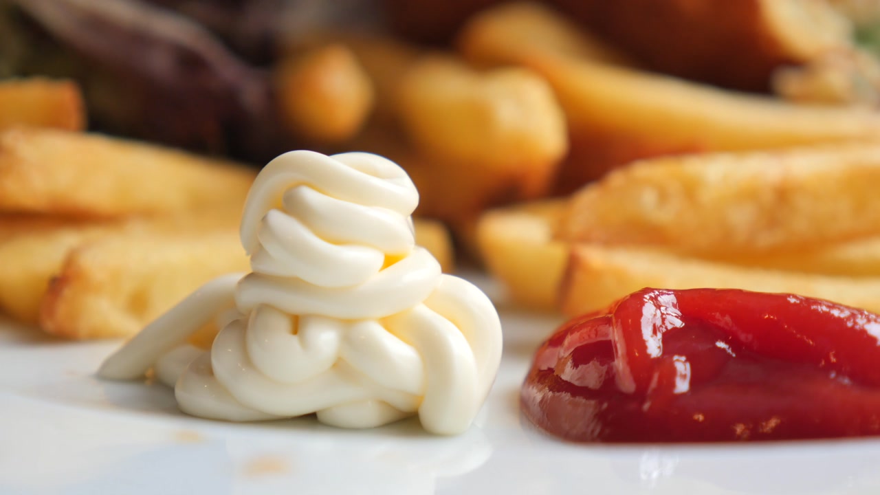 Squeezing Mayonnaise onto a Plate with Ketchup and French Fries