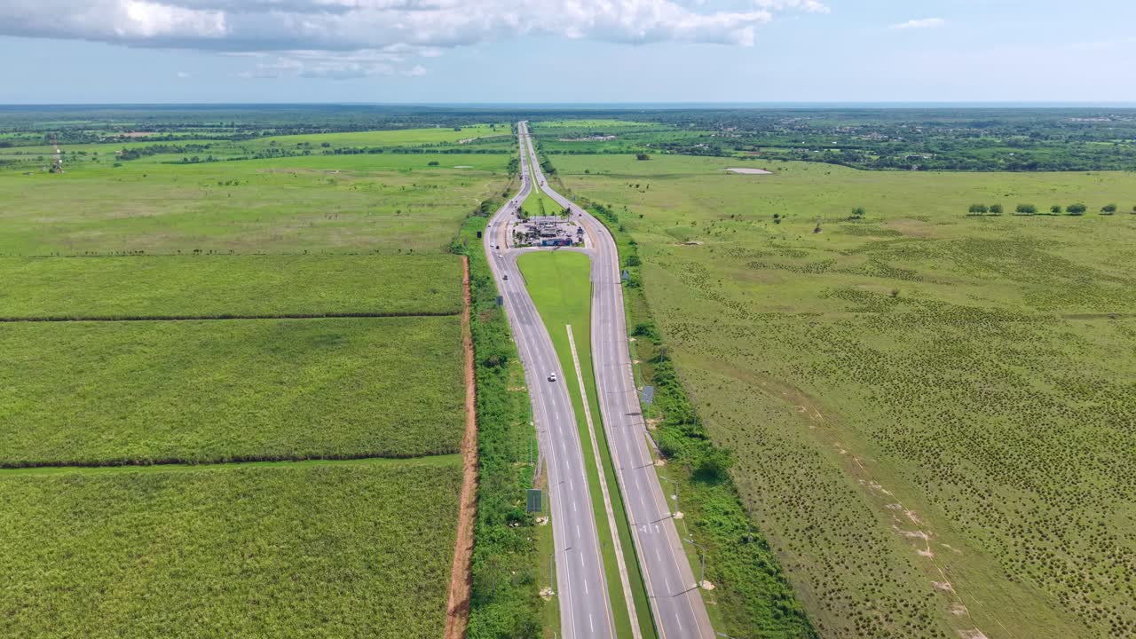 Autopista del Coral highway and gas station, surrounded by sugarcane fields, Dominican Republic. Aerial forward