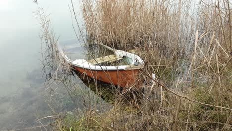 close-up-panning-shot-of-a-forgotten-rowboat-in-water-partially-sunken