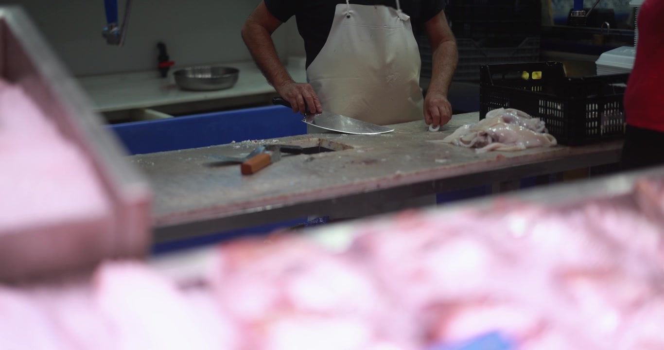 Peixeiro limpando lulas frescas no balcão de um mercado