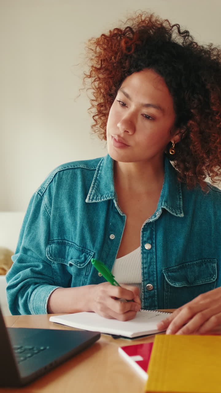 Young Woman Taking Notes While Studying at Home Desk