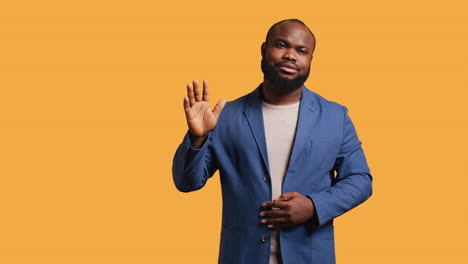 man reluctantly doing salutation hand gesture, saying goodbye, studio background