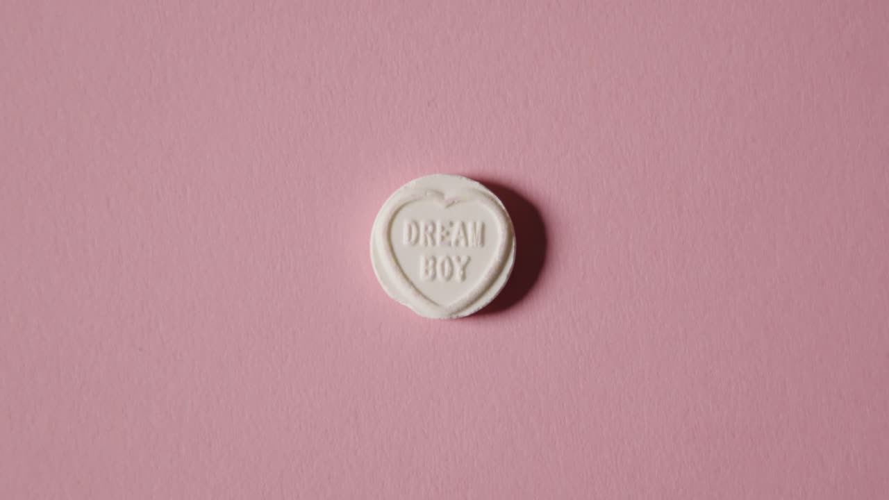 Hand Picking Up Heart Candy With Dream Boy Message On Pink Background