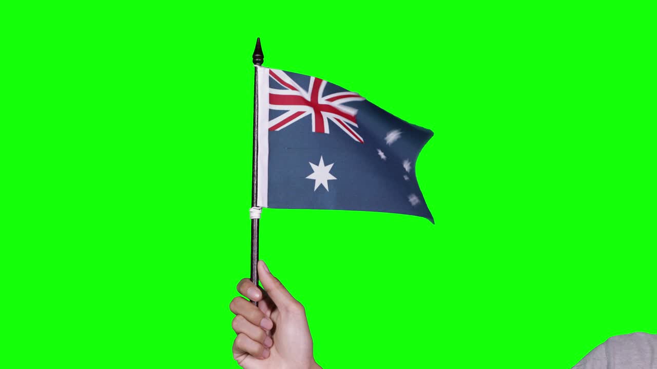 Mão desconhecida segurando uma bandeira do Reino Unido tremulando.