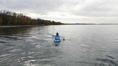 young woman kayaking on a large, blue lake in alberta, canada