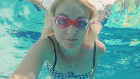 A-Young-Woman-Shoots-Herself-In-The-Video-Under-The-Water-Floats-In-The-Pool-Looks-Into-The-Camera-W