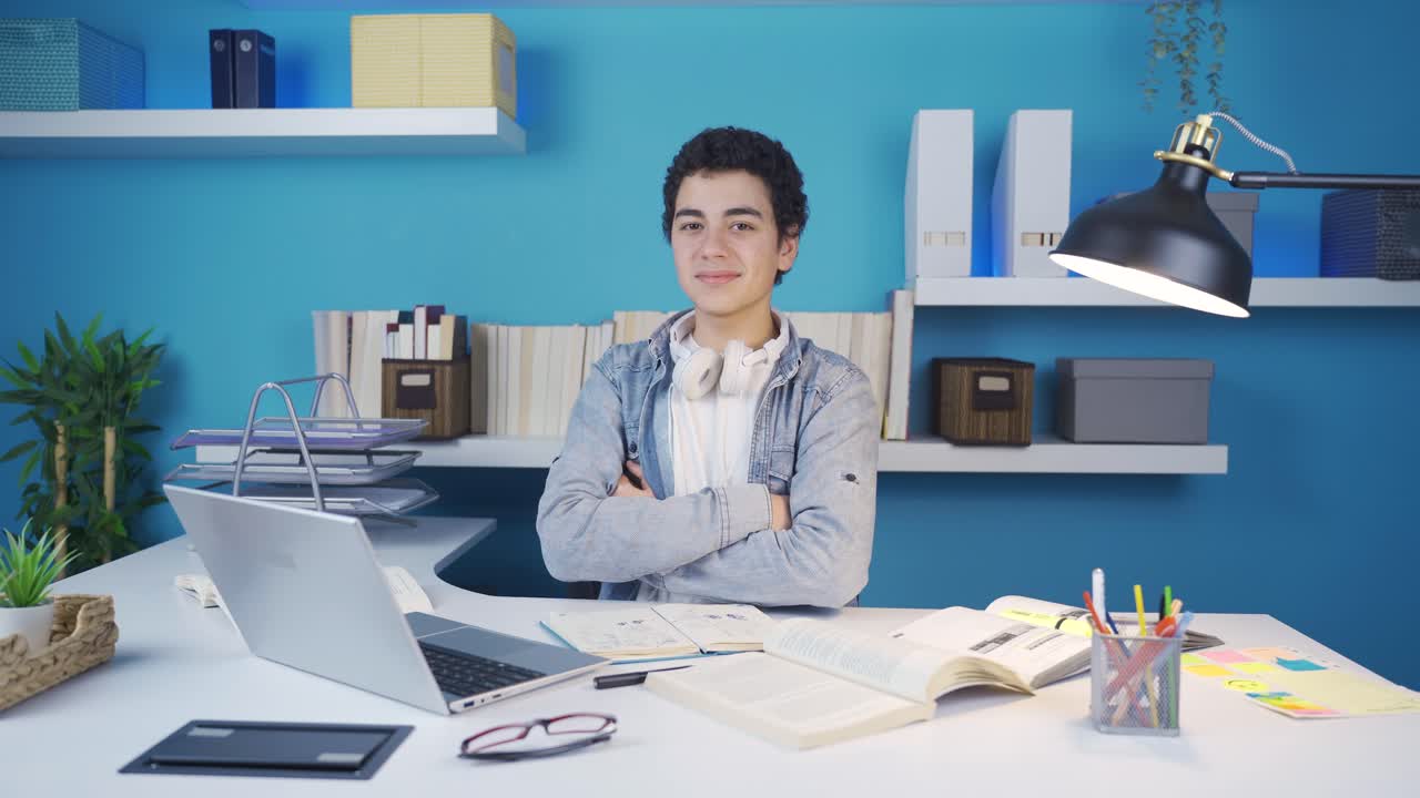 노트북을 보면서 자신감 있는 표정으로 미소 짓고 카메라를 쳐다보는 젊은이