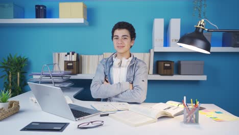 joven sonriendo y mirando a la cámara con una mirada confiada mientras mira la computadora portátil