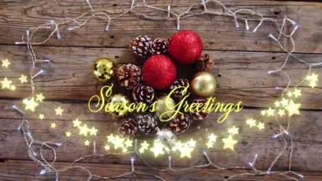 Animation-of-text,-season's-greetings,-in-yellow,-over-star-string-lights-and-christmas-decorations