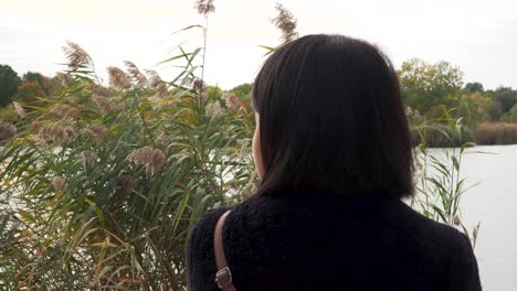 young girl sitting in front of lake looking around back view