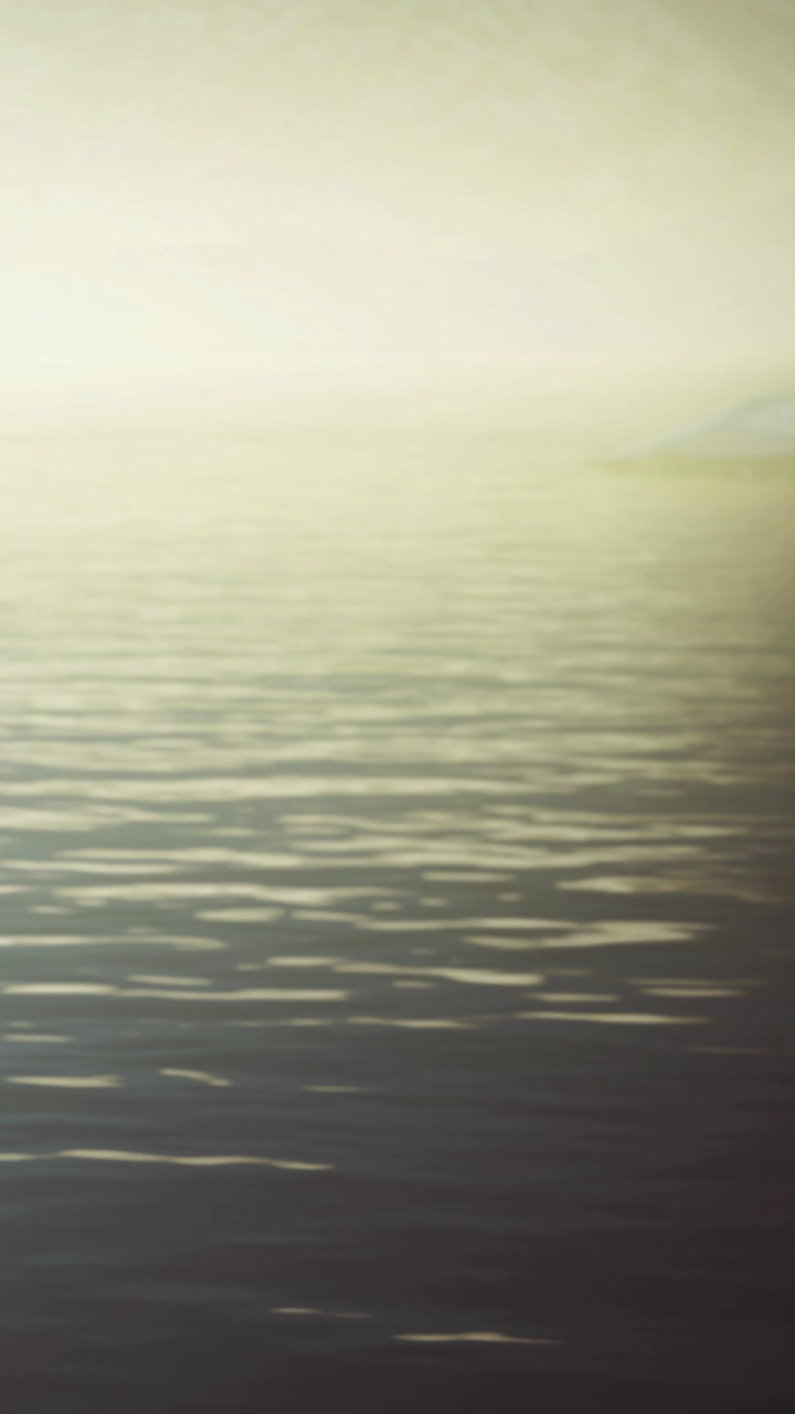 Sunrise over water with ripples seen from a distant shore during morning light