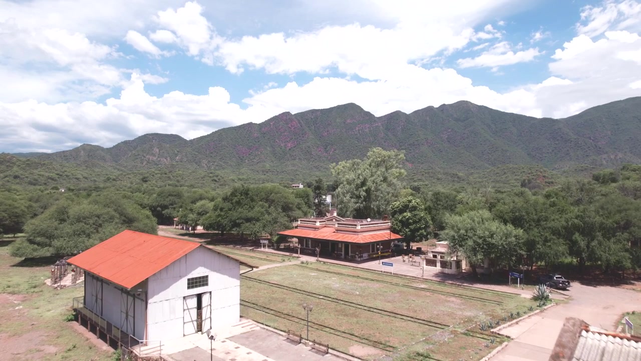 Vista aerea 4K con drone di Alemania, Salta, Argentina. Storico villaggio ferroviario con una vecchia stazione, un ponte e un fiume circondato da montagne verdi e lussureggianti e valli panoramiche dell'Argentina settentrionale