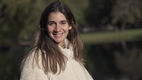 bela jovem caucasiana olhando para a câmera e sorrindo durante o dia ensolarado na natureza, retrato de perto