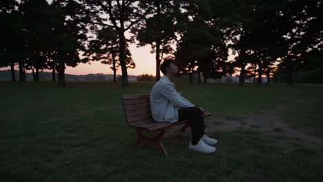 man sitting on a park bench at sunset