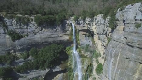 fast aerial back reveal of a breathtaking waterfall on a rocky steep cliff