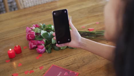 Happy-biracial-woman-making-valentine's-day-video-call-on-smartphone,-with-copy-space-on-screen