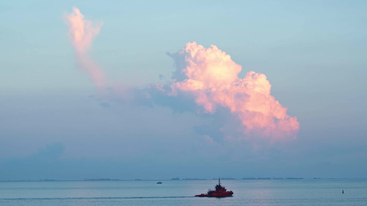 구름과 배와 함께 바다 위에 해가 뜨는 것