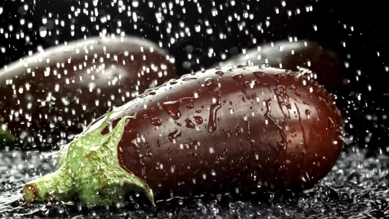 Slow motion av vattendroppar som faller på färsk aubergine