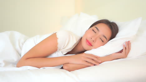 Motionless-Asian-woman-sleeping-on-a-side-in-white-king-size-bed-daytime---panning-shot