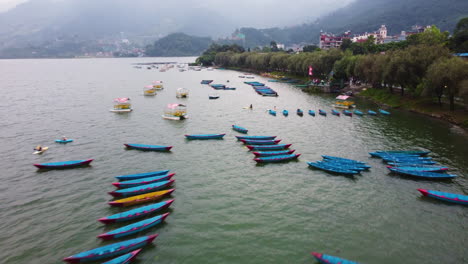 Drone-over-lake-Phewa-in-Nepal-with-anchored-boats-and-mountain-range-in-Background---flyover---Nepal,Asia